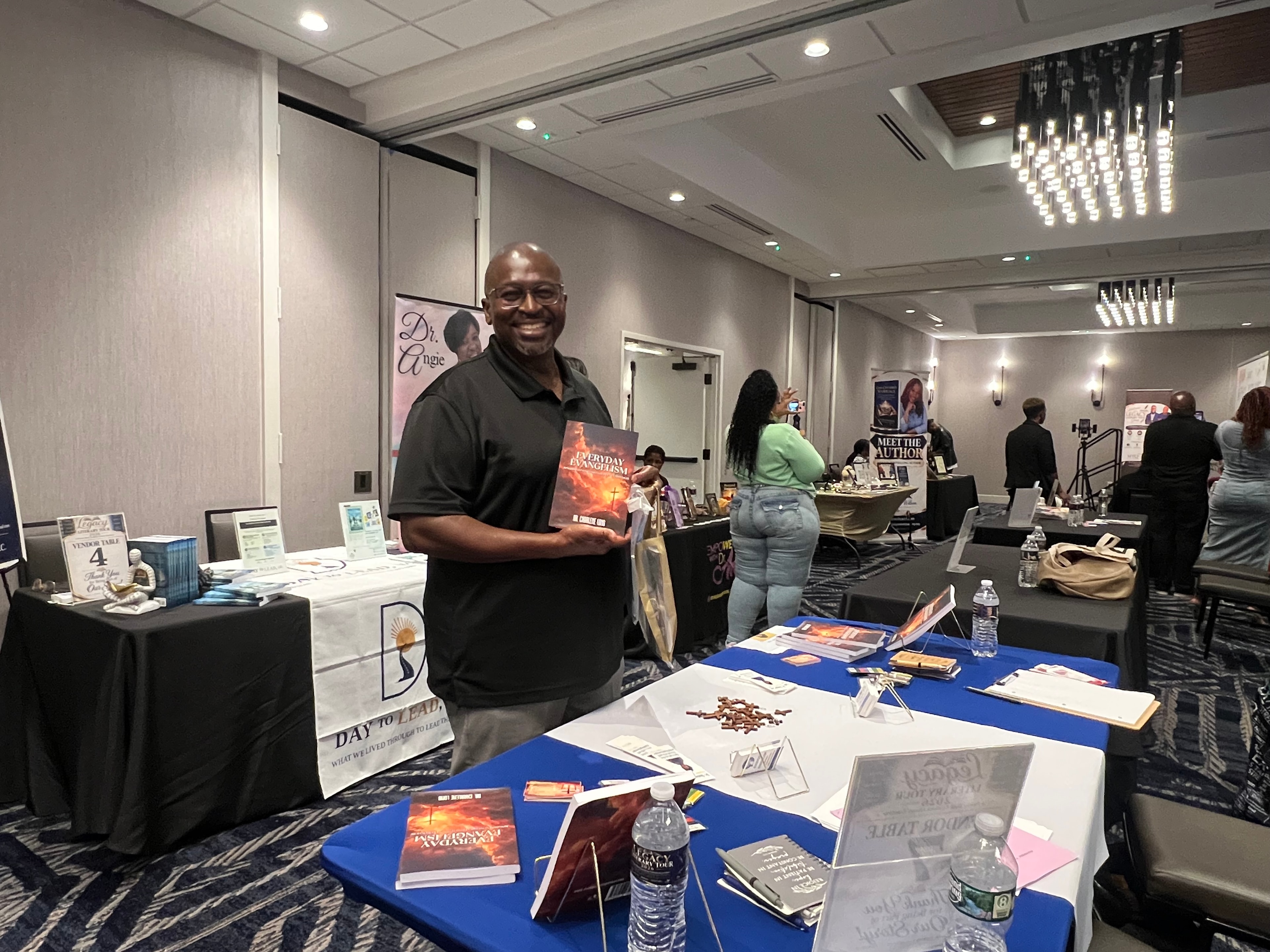 Male customer holding Everyday Evangelism at the Legacy Literary Tour 2026 vendor hall